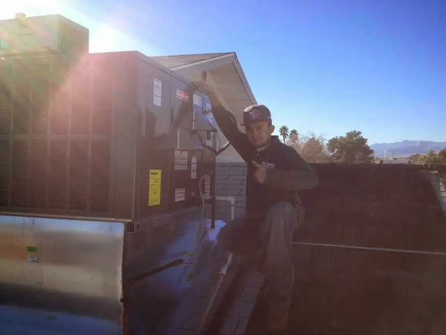 HVAC technician performing AC Tune-Up on a rooftop unit in Oconomowoc